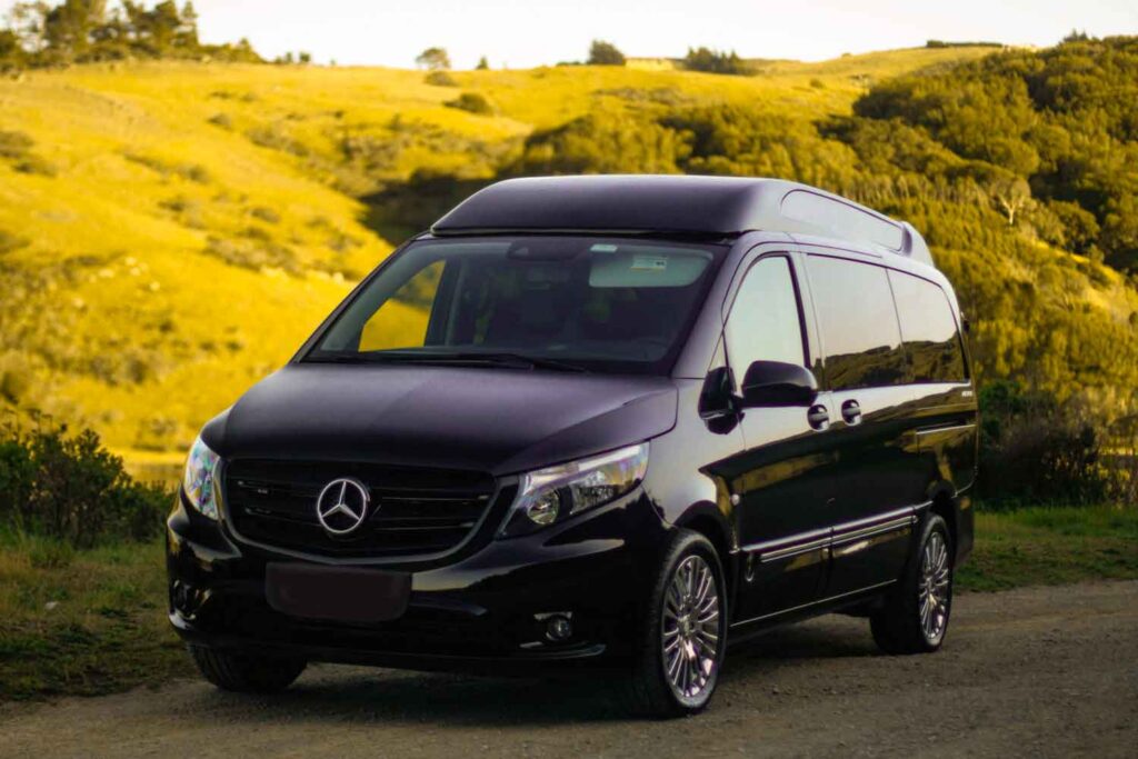 Exterior photograph of the left side of a black Mercedes Metris parked in a vineyard with afternoon light.